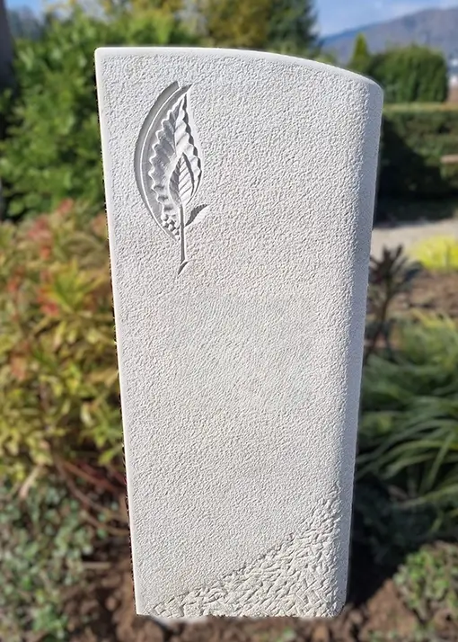 Weißer Grabstein mit einem eingravierten Blatt